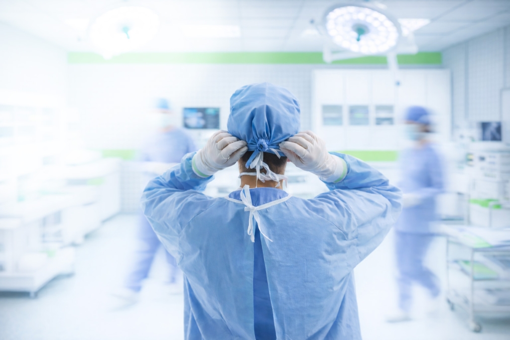 Surgeon adjusting surgical cap while preparing for an operation in a modern operating room.